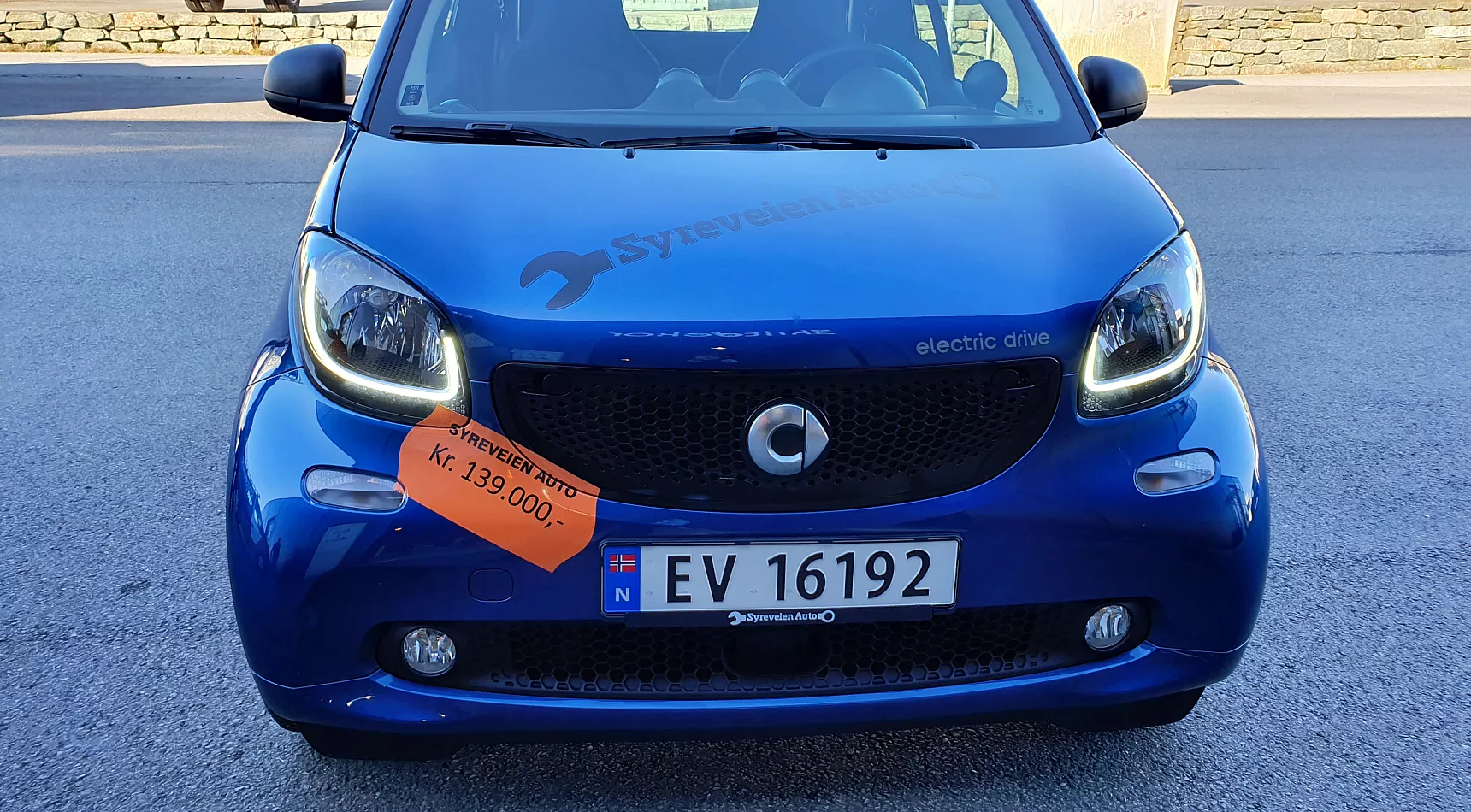 Blå bil som er til salgs for kr 139000 og som har fått en stor prislapp på fronten
